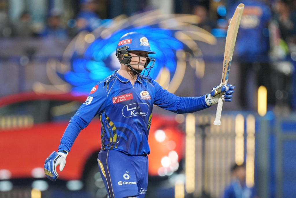 Mumbai Indians batsman raising his bat to celebrate a fifty or century during an IPL night match at Wankhede Stadium
