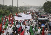 ‘No India-US Trade Deal, No Retreat’: Samyukt Kisan Morcha Announces Nationwide Farmers’ Agitation From November 26 Thousands of farmers carrying green and red flags march towards New Delhi during a Samyukt Kisan Morcha protest with tractors and banners.